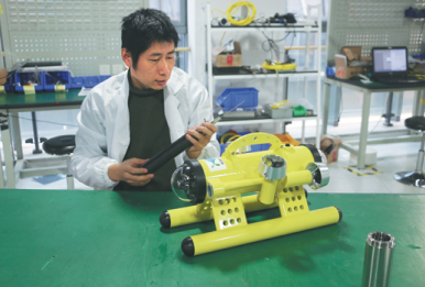 Fan Ping, chief technology officer at Qingdao Robotfish Marine Technology Co Ltd, debugs the Coral Guard robot. [Photo/China Daily]